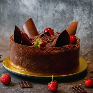 A beautifully decorated chocolate cake adorned with fresh strawberries on a rustic plate.